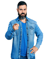 Hispanic man with beard pointing with finger to camera clueless and confused expression. doubt...
