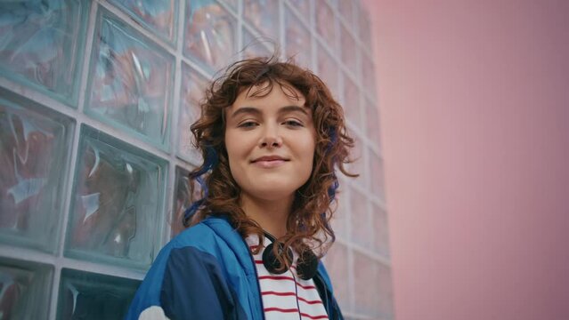 Smiling teen looking camera leaning on glass wall urban building zoom in.