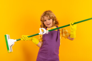 Little kid cleaning at home. Child doing housework having fun. Studio isoalted portrait of child housekeeper with wet flat mop on yellow background.