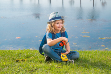 Little child with backpack and binoculars. Imagination or exploration in park. Happy child playing...