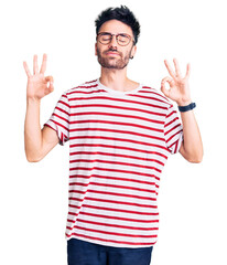Fototapeta premium Young hispanic man wearing casual clothes relaxed and smiling with eyes closed doing meditation gesture with fingers. yoga concept.