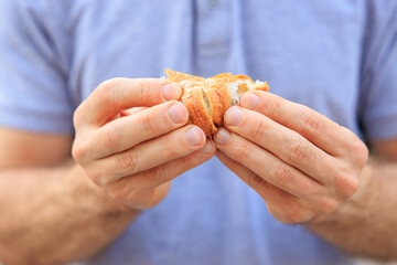 A man's hand holds a mini puff pastry with cheese, snack and fast food concept. Selective focus on hands