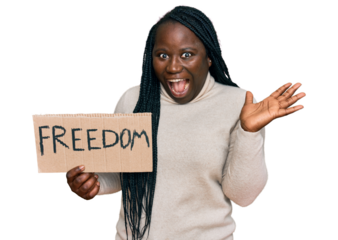 Young black woman with braids holding freedom banner celebrating victory with happy smile and winner expression with raised hands