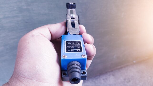 The technician hold the limit switch component electrical automation switching. 