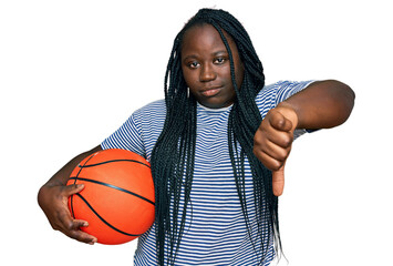 Young black woman with braids holding basketball ball with angry face, negative sign showing...