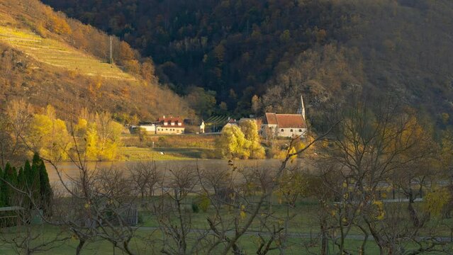 Old historic church, St. Johan Mauerthale, sitting on the banks of the Danube River next to the hillside on a picturesque autumn day, Wachau Valley, Austria