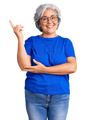 Senior woman with gray hair wearing casual clothes and glasses smiling happy pointing with hand and finger to the side