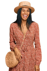 Young african american woman wearing summer hat winking looking at the camera with sexy expression,...