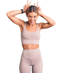Fototapeta na wymiar Beautiful caucasian woman wearing sportswear posing funny and crazy with fingers on head as bunny ears, smiling cheerful