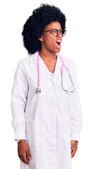 Young african american woman wearing doctor coat and stethoscope angry and mad screaming frustrated and furious, shouting with anger. rage and aggressive concept.