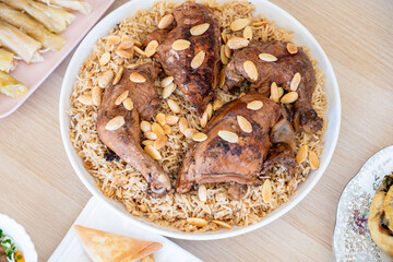 Arabian rice bowl with chicken and almond topping on wooden table from top view