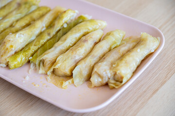 dish of Stuffed Cabbage Rolls on wooden table and pink dish, traditional jordanian recipe