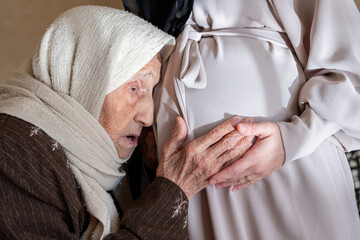 muslim old woman feeling excited for her new grandson touch her daughter tummy to feel fetus...
