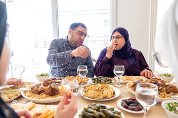 Arabian family having dinner together on wooden table with father,mother,grandfather,grandmother and son
