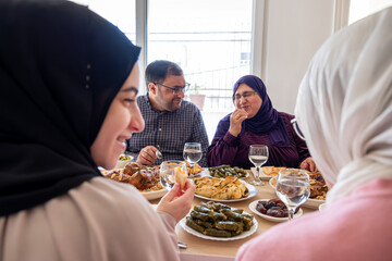 Arabian family having dinner together on wooden table with father,mother,grandfather,grandmother and son
