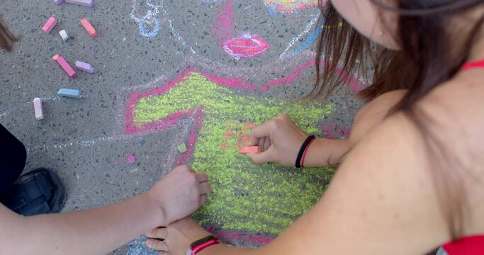 Joint leisure time drawing with crayons on the road. Drawing orange pattern lines. Using colorful crayons outdoors.