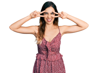 Beautiful hispanic woman wearing bohemian and hippie style doing peace symbol smiling and laughing hard out loud because funny crazy joke.