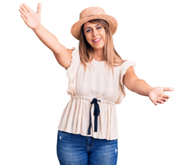 Young beautiful woman wearing summer hat and t-shirt looking at the camera smiling with open arms for hug. cheerful expression embracing happiness.