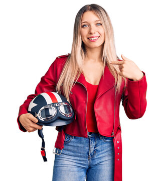 Young beautiful blonde woman holding motorcycle helmet pointing finger to one self smiling happy and proud