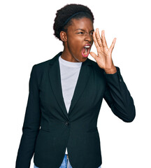 Young african american girl wearing business clothes shouting and screaming loud to side with hand...
