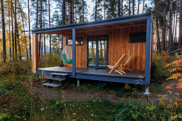 Vacation rental forest lodge countryside cabin with big windows and terrace among trees for holidays in the wilderness. Modern cottage in wild pine forest