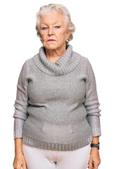 Senior grey-haired woman wearing casual winter sweater relaxed with serious expression on face....