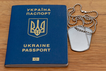Ukrainian passport and army medallion on textured wooden background. Concept: military conscription...