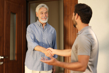 Friendly relationship with neighbours. Happy men shaking hands near house outdoors