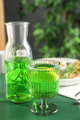 Delicious drink with tarragon in glass on green table. Space for text