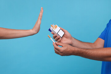 Stop smoking concept. Woman refusing cigarettes on light blue background, closeup