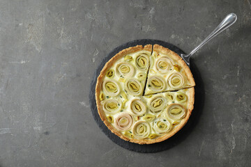 Tasty leek pie with cake server on dark textured table, top view. Space for text