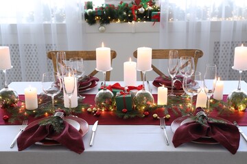 Christmas table setting with burning candles and festive decor