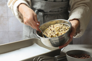 Woman making chocolate chip cookie dough at table, closeup