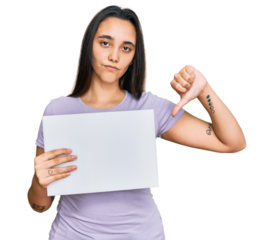 Young hispanic woman holding blank empty banner with angry face, negative sign showing dislike with thumbs down, rejection concept