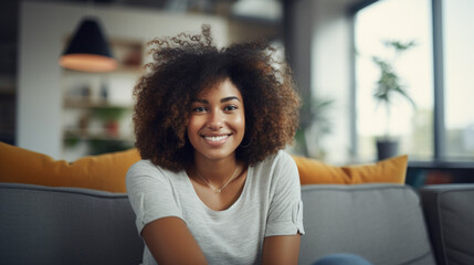 Portrait of a young smiling African American woman sitting on a couch in her home