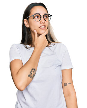 Young hispanic woman wearing casual white t shirt thinking worried about a question, concerned and nervous with hand on chin