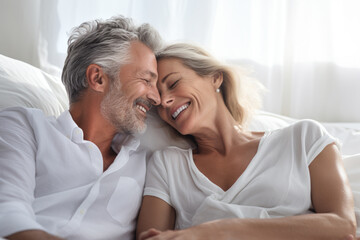 Retired middle age couple smiling and happy embrace on a white couch