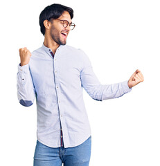 Handsome hispanic man wearing business shirt and glasses dancing happy and cheerful, smiling moving casual and confident listening to music