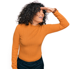 Young hispanic woman wearing casual clothes very happy and smiling looking far away with hand over head. searching concept.