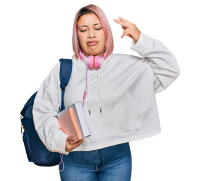 Hispanic woman with pink hair wearing student backpack and headphones shooting and killing oneself pointing hand and fingers to head like gun, suicide gesture.