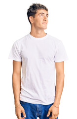 Young handsome man wearing casual white tshirt smiling looking to the side and staring away thinking.