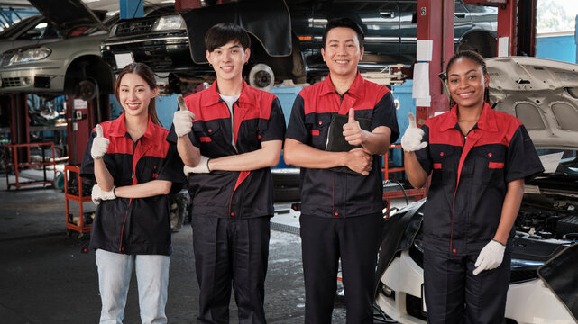 Portrait of multiracial professional mechanic team thumbs up and look at camera, work at car service garage, happy maintenance jobs, check and repair occupation in automotive industry business. © tigercat_lpg