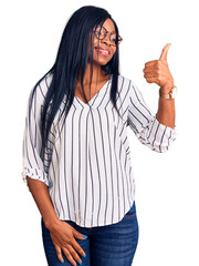 Young african american woman wearing casual clothes and glasses looking proud, smiling doing thumbs up gesture to the side