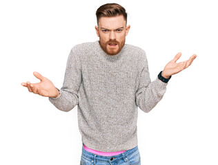 Young redhead man wearing casual winter sweater clueless and confused with open arms, no idea...