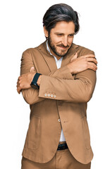 Fototapeta premium Young hispanic man wearing business clothes hugging oneself happy and positive, smiling confident. self love and self care