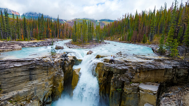Sunwapta Falls Jasper National Park Canada. The Canadian Rockies during the Autumn fall season. A couple of men and women visiting Sunwapta Falls standing on the edge of the waterfall
