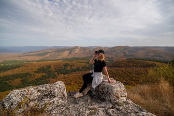 woman on mountain peak looking in beautiful mountain valley in autumn. Landscape with sporty young woman, blu sky in fall. Hiking. Nature