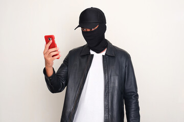 An online scammer looking to mobile phone that he hold with threatening gesture