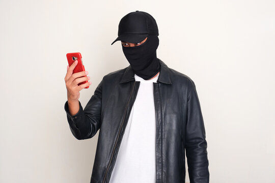 An online scammer looking to mobile phone that he hold with threatening gesture