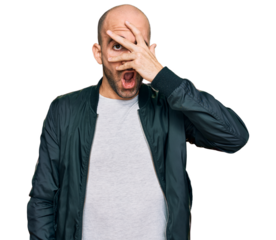 Young hispanic man wearing casual clothes peeking in shock covering face and eyes with hand, looking through fingers with embarrassed expression.